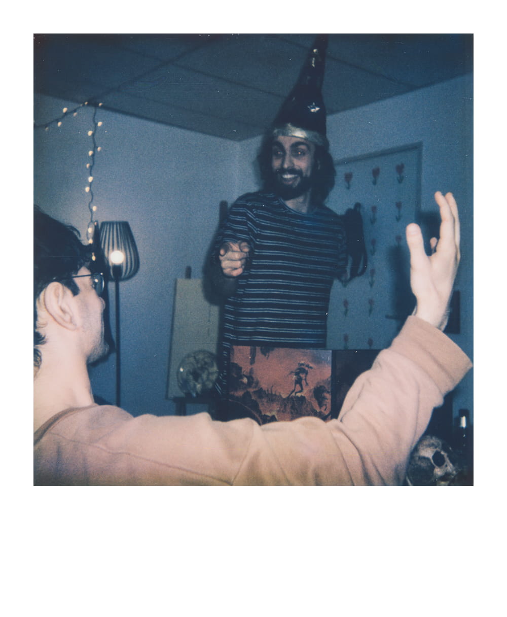 Dungeon Master wearing a wizard hat, narrating a dnd adventure, engaging with players in a decorated room.
