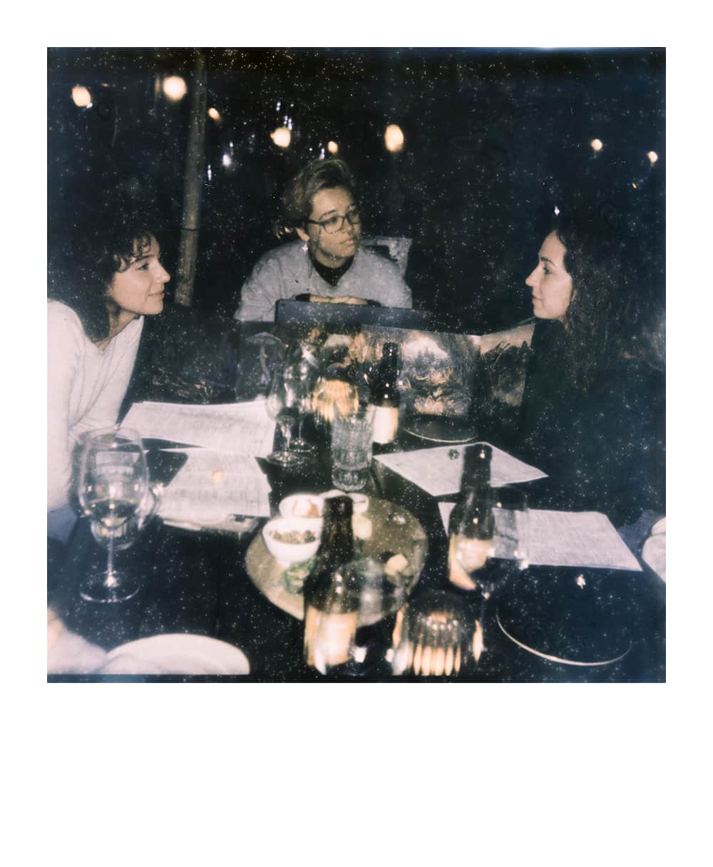 A group enjoying a tabletop RPG in a café, seated around a table filled with snacks, guided by a professional Game Master behind a DM screen.